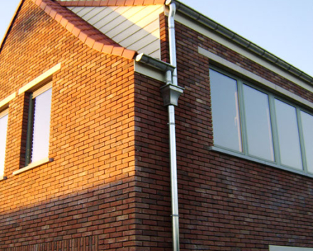 Halfronde hanggoot in zink met inox goothaken. Afvoerbuis in zink met inox scharnierbeugels